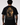 A man viewed from behind wearing a black t-shirt with a large, detailed graphic print on the back. The graphic features a golden, fiery, and dark illustration of a figure with a halo, with Greek and English text below reading 'ΟΤΤΕΝΑΙ ΓΤΩΡΟΜΑΙ ΓΙΝΕΤΑΙ ΣΤΟΥΣ - SPARTANS SPORTWEAR - EST.